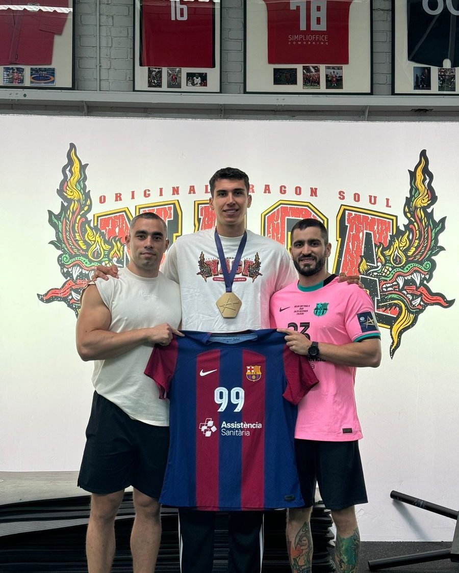 Jugador de balonmano con su medalla y una camiseta del Barça, ante el mural del dragón de Naga
