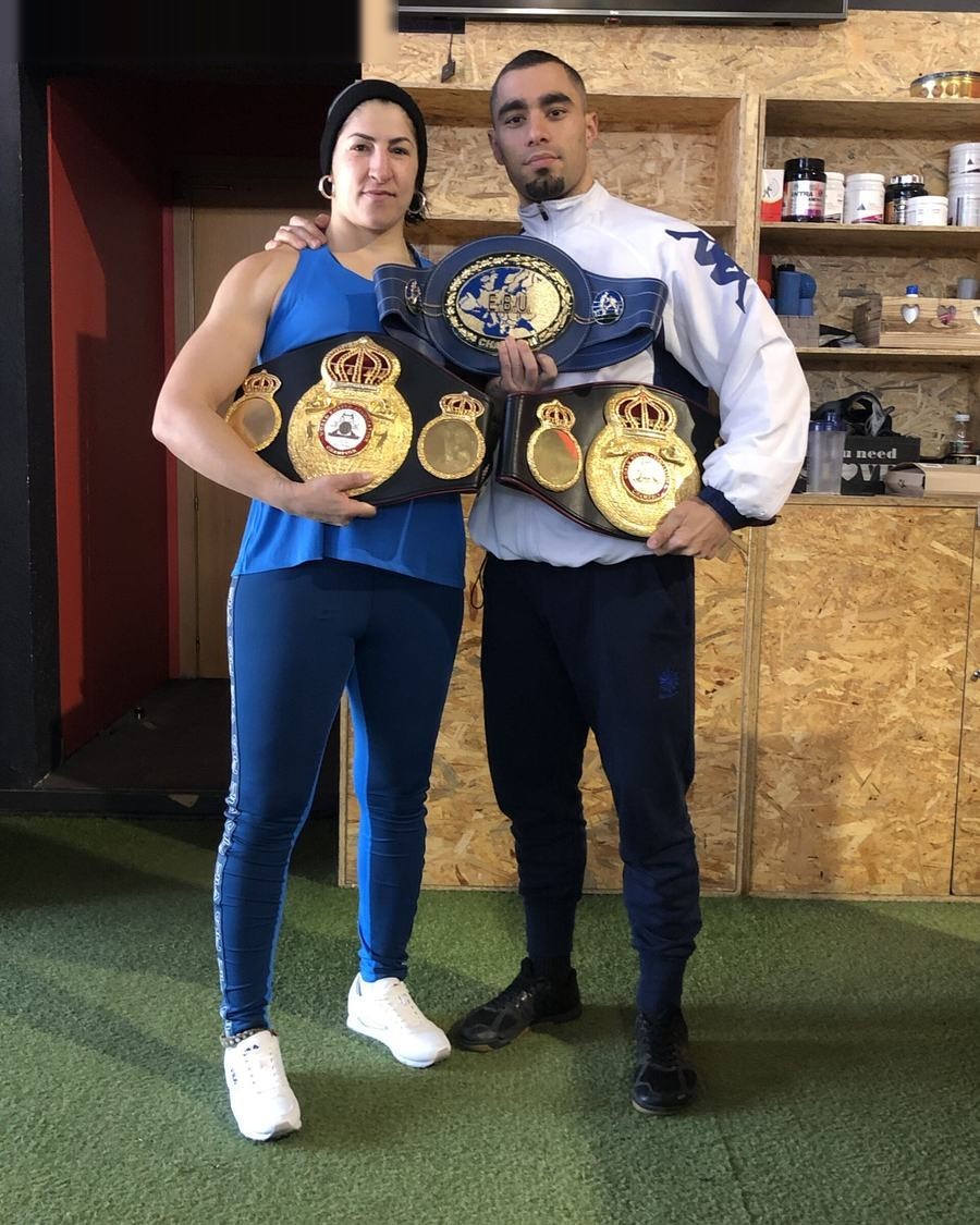 Una boxeadora y un boxeador con sus cinturones de campeones en Naga