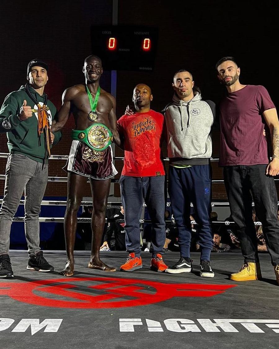 El equipo de Naga en el ring con un luchador que lleva su cinturón y su medalla