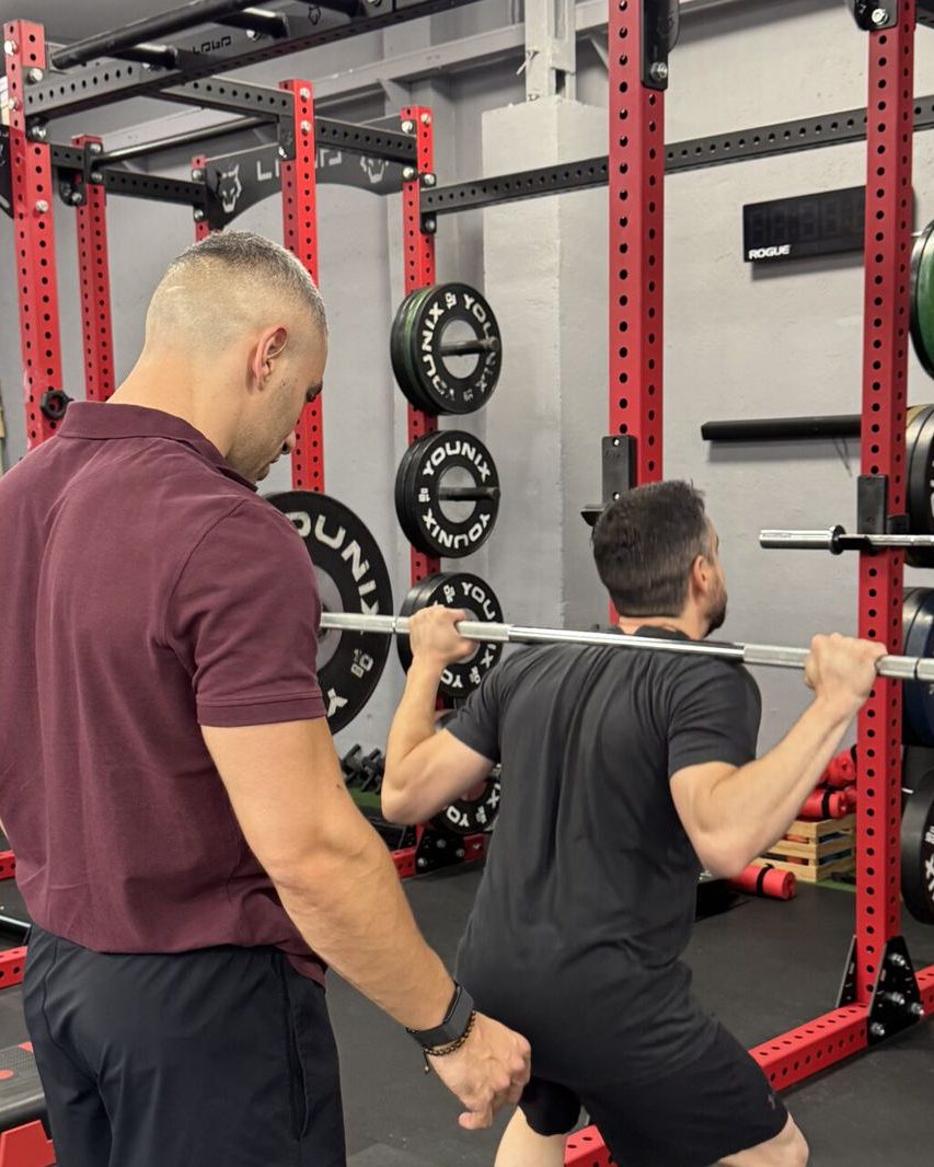 Entrenador de Naga corrigiendo una sentadilla